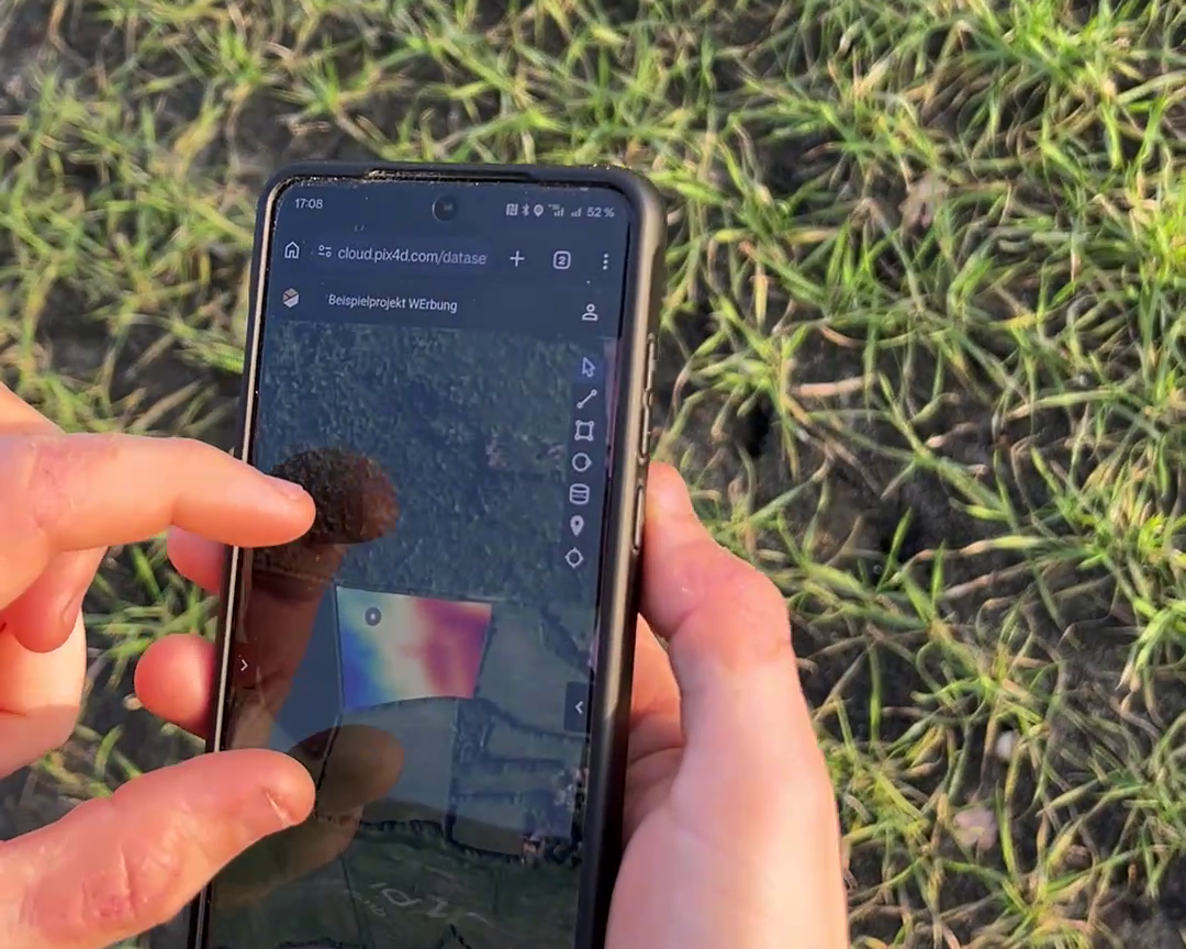 Handy in der Hand eines Landwirts, welches ein digitales Oberflächenmodell anzeigt.